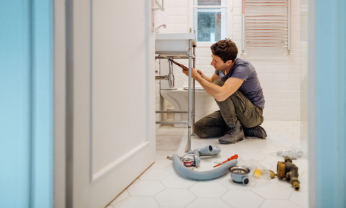 A plumber working underneath a sink.